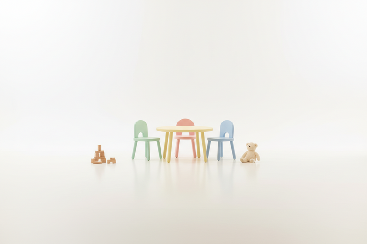 Drei Kinderstühle in Pastellfarben um einen kleinen runden Tisch, daneben Holzbausteine und ein Teddybär vor hellem Hintergrund.