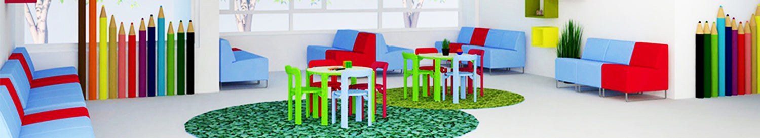 Bunter Kinderbereich mit kleinen Tischen und Stühlen, roten und blauen Sofas, grünen Teppichen und Wanddekor in Form grosser Buntstifte.